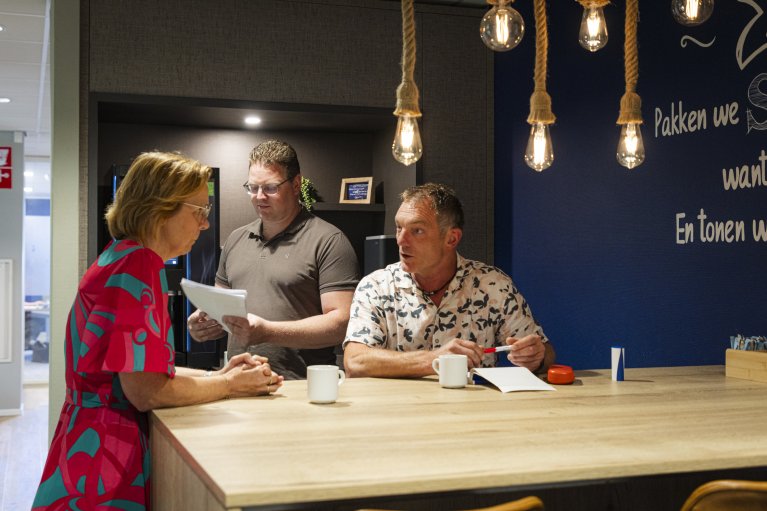 Collega's zitten te overleggen aan tafel